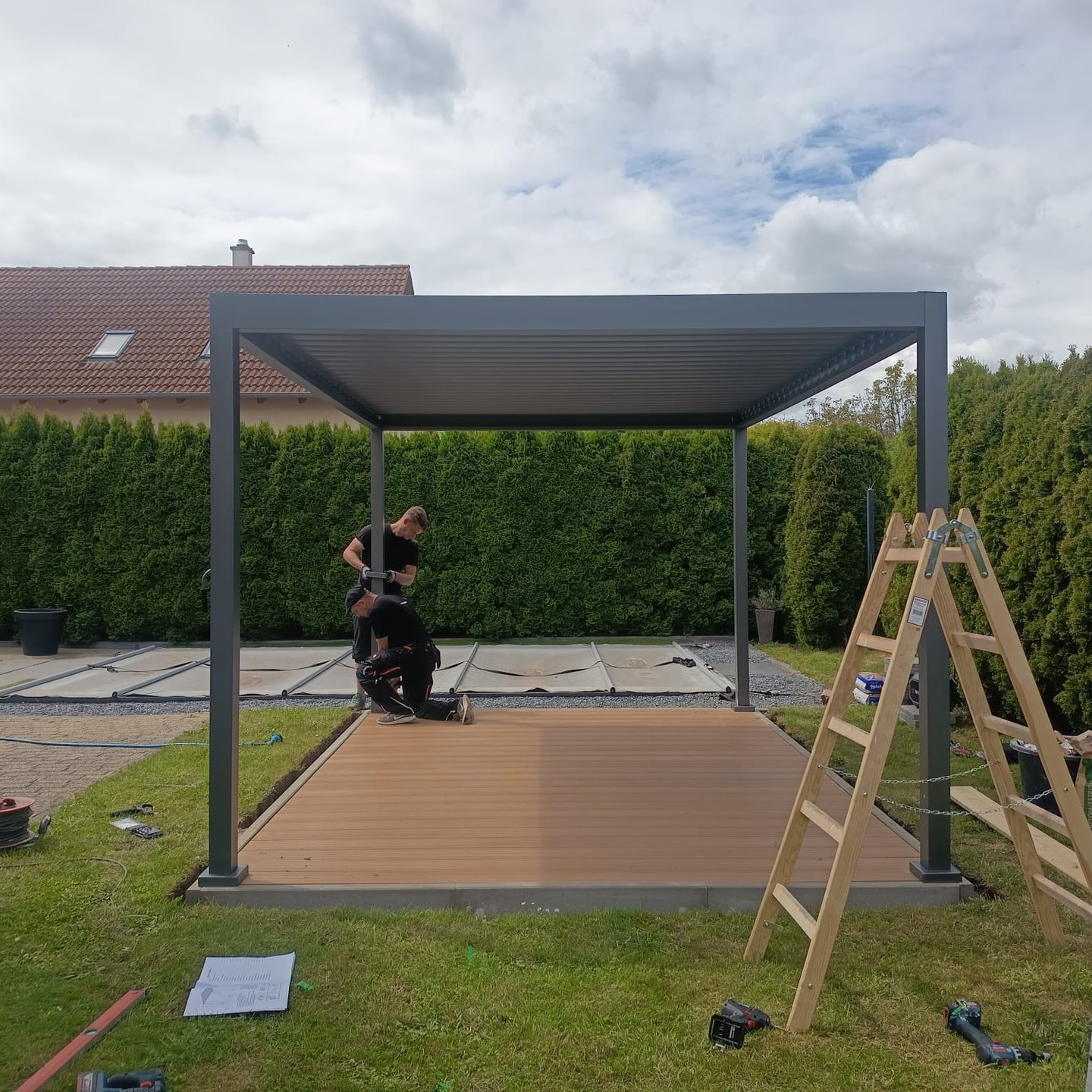 Monteur baut Terrasse mit Seitenmarkise im Garten