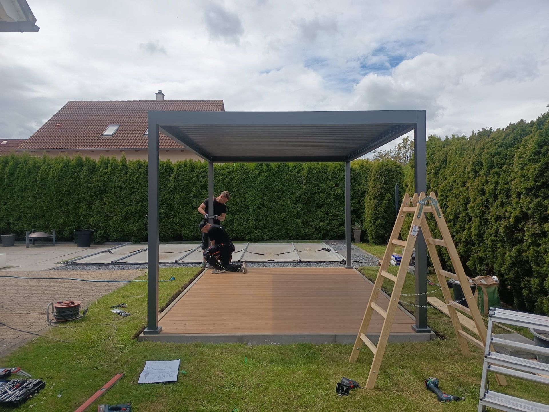 Gartenarbeiter errichten eine Pergola auf einer Holzterrasse