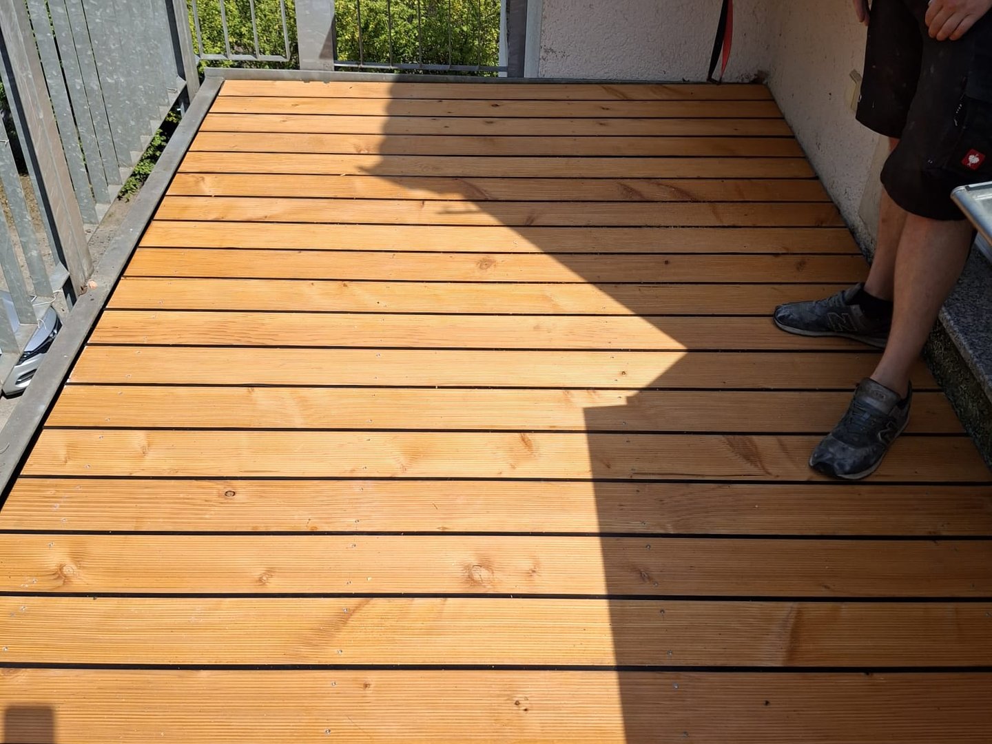 Neue Holzdielen-Terrasse auf einem Balkon im Sonnenlicht